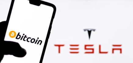 Bitcoin logo on a smartphone against Tesla logo in the background. Elon Musk recently invested $1.5 billion in Bitcoin, opening possibility of Bitcoin transactions to purchase Tesla automobiles.