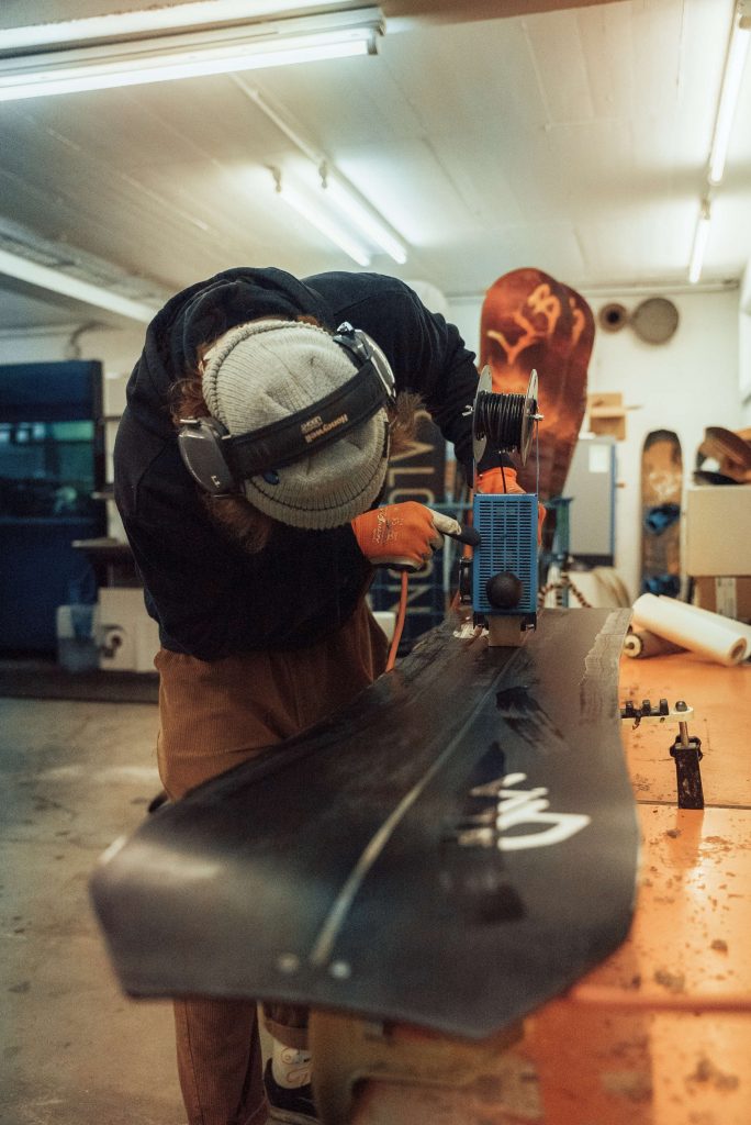 Ein Handwerker schleift ein Snowboard