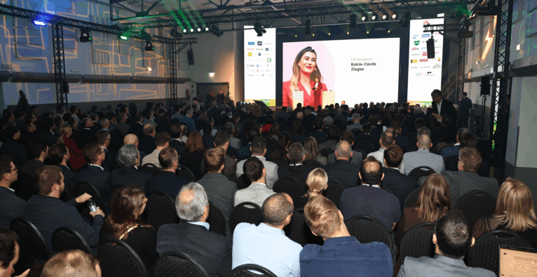Ein Foto vom Technology Impact Summit mit Moderatorin Katrin-Cécile Ziegler auf der Bühne