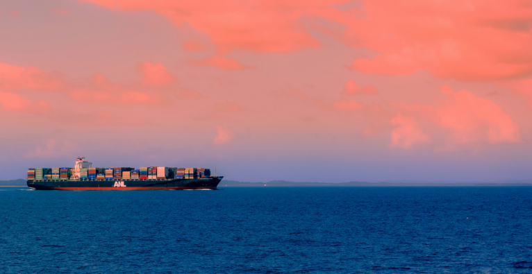 Frachtschiff auf offener See im Sonnenuntergang