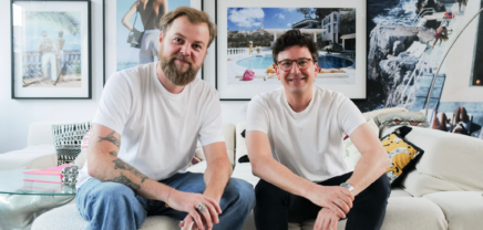Synfia.ai Gründer René Mähr und Simon Rutar sitzen auf einer Couch und lachen in die Kamera.