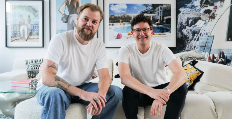 Synfia.ai Gründer René Mähr und Simon Rutar sitzen auf einer Couch und lachen in die Kamera.