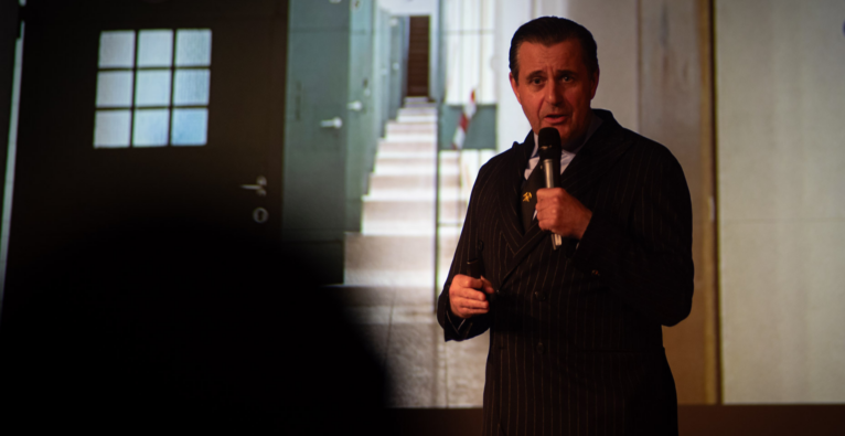 Chris Müller steht vor einer Präsentation und redet in ein Mikro. (c) Tobias Zachl