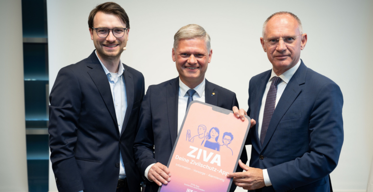 ÖZSV Bundesgeschäftsführer Josef Farda (li.) ÖZSV Präsident Andreas Hanger (Mitte) Bundesminister Gerhard Karner (re.) präsentieren die ZIVA App. Sie halten gemeinsam ein Bild der APP hoch
