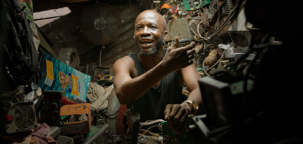 Ein Mann in Accra sitzt in einer Garage und repariert einen alten Computer (c) refurbed