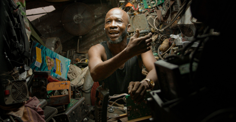 Ein Mann in Accra sitzt in einer Garage und repariert einen alten Computer (c) refurbed